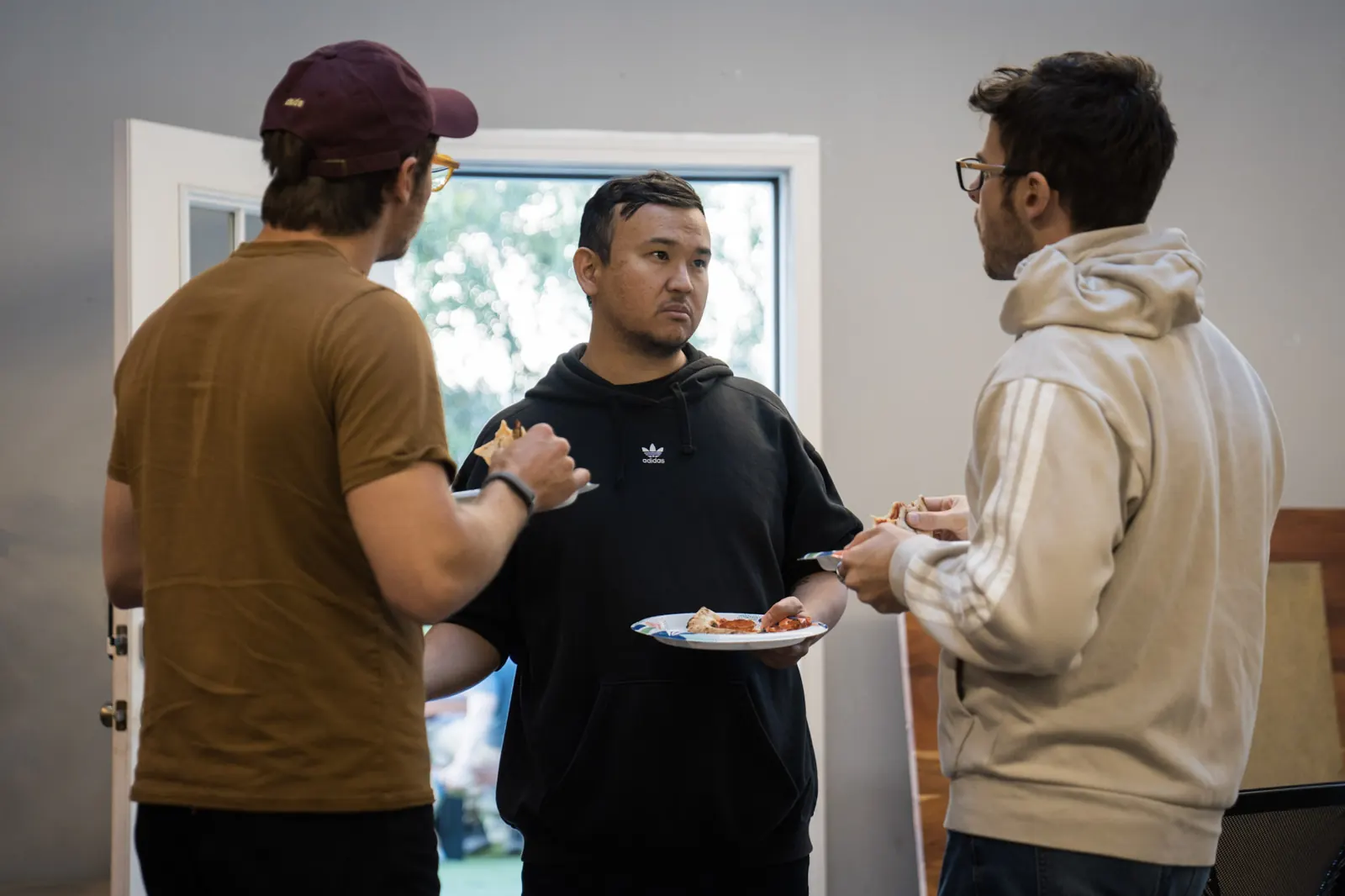 Three attendees talking over pizza during arrivals at Wefunder