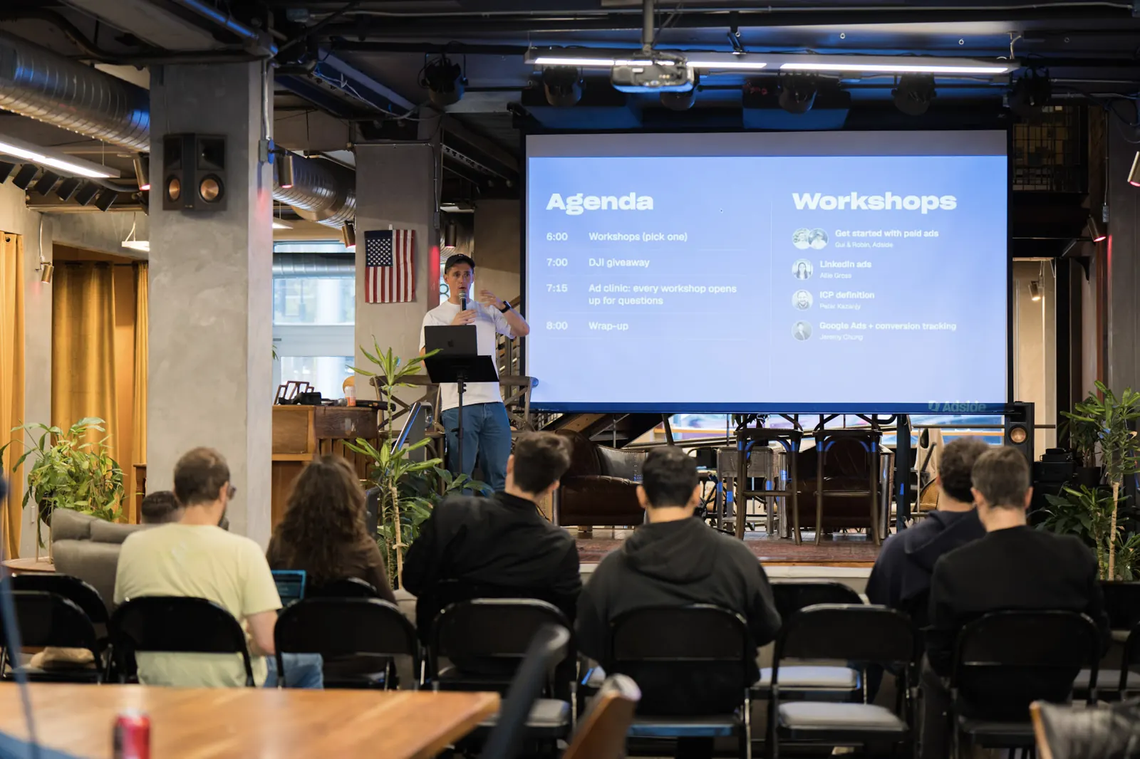 Robin Choy giving the intro talk at Wefunder, with the evening's agenda and the four workshops on the big screen
