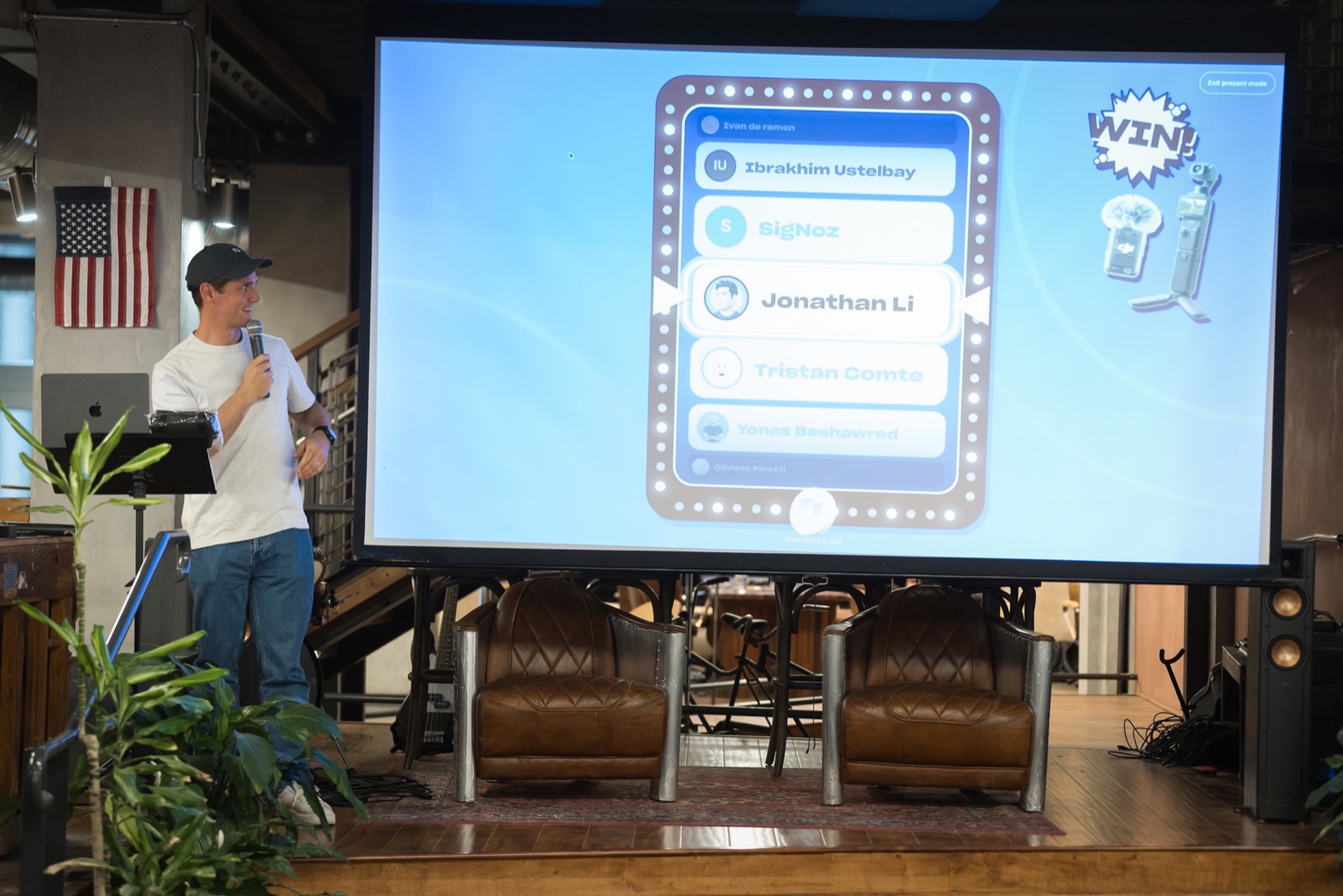 Robin Choy on stage spinning the giveaway raffle wheel on the big screen